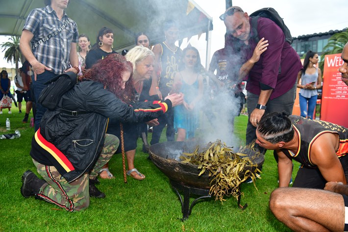 People enjoying smoke from fire at the Welcome Ceremony